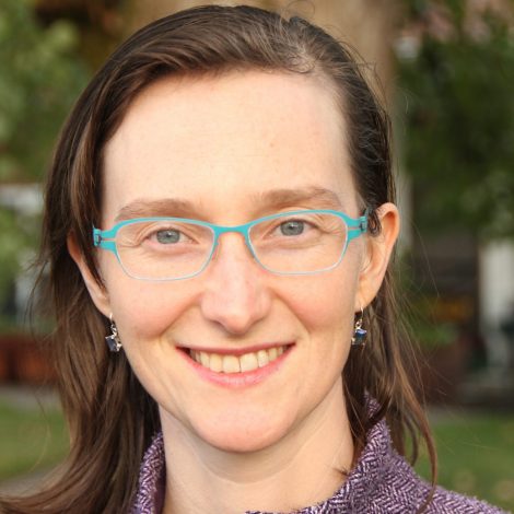 Headshot of Anchen with blue-rimmed glasses